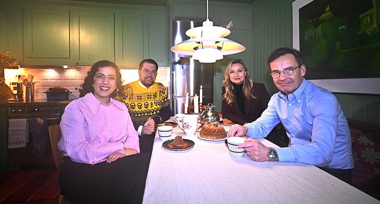 De fyra partiledarna sitter vid ett bord i ett kök. De ser glada ut.