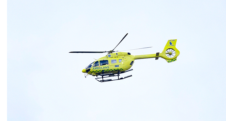 En ambulanshelikopter som flyger. Den är gul.
