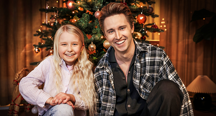 De är bredvid varandra framför en julgran.