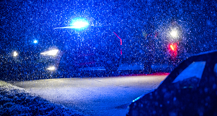Snö faller vid en väg.