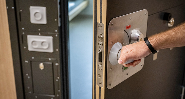 En person håller i dörren till en cell på ett häkte där man låser in folk.