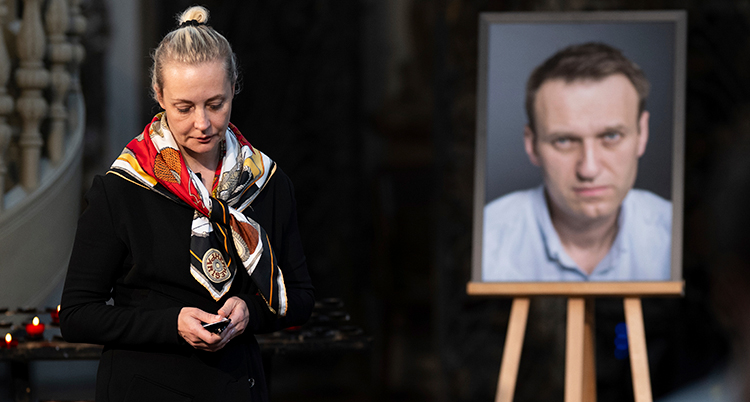 Julia står bredvid en bild av hennes man Aleksej.