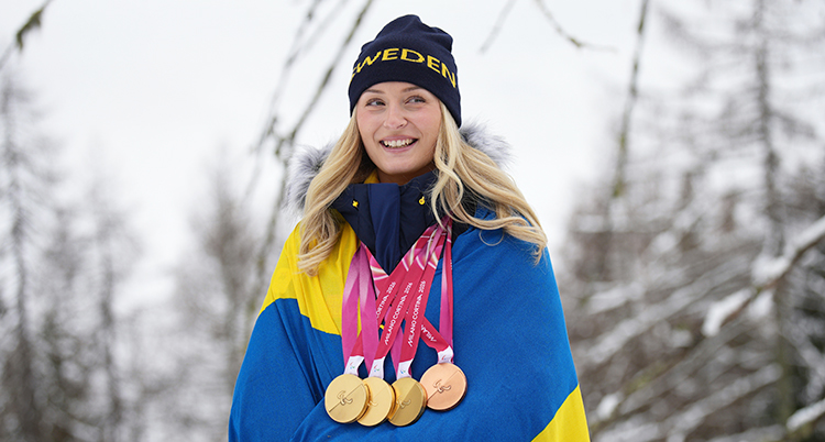 Hon är glad. Hon har fyra medaljer runt halsen.
