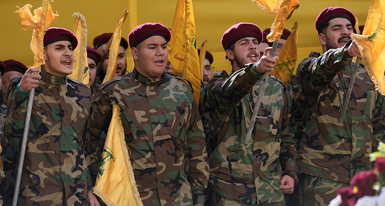 Fyra personer i militärkläder. De har röda baskrar på huvudet. De har gula flaggor.