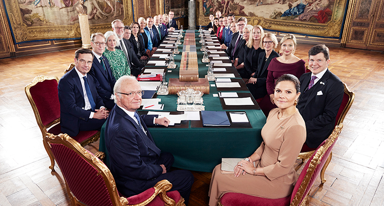 De sitter vid ett långt bord.