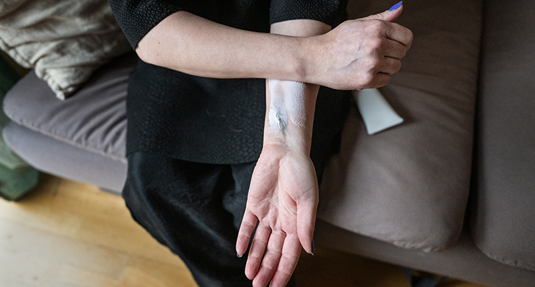 Hon stryker kräm på sin arm.