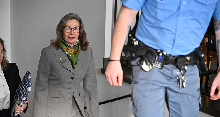 Hon går upp för en trappa. Framför henne är en vakt.