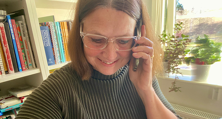 Hon håller i en telefon och tittar på sin tröja.