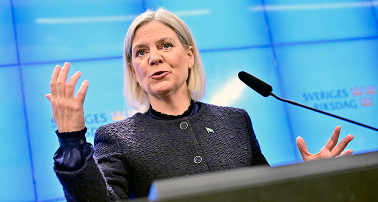 Hon står och pratar i en mikrofon på en träff med journalister.