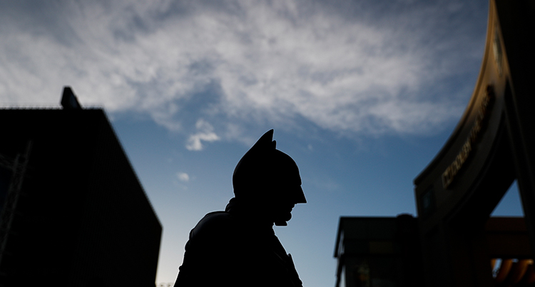 En svart figur som ser ut som Batman syns mot en blå himmel.