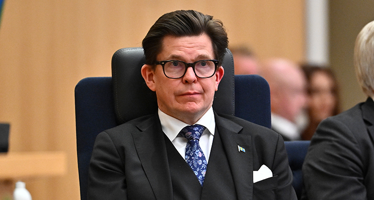 Han sitter och tittar rakt fram.