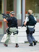 Poliser med vapen undersöker penga-lagret i Stockholm efter rånet. Foto: Pontus Lundahl/Scanpix