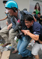 En skadad demomstrant i Bangkok får hjälp av en fotograf. Foto: Sakchai Lalit/Scanpix