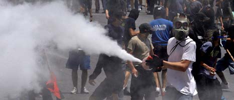 En demonstrant sprutar skum från en brandsläckare mot polisen under gårdagens våldsamheter i Grekland. FOTO: Petros Giannakouris/Scanpix