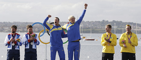 Fredrik Lööf och Max Salminen står högst på pallen och jublar över Sveriges första OS-guld i årets tävlingar. FOTO: Bernat Armangue/SCANPIX