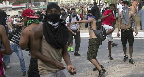 Demonstranter kastar stenar mot poliserna vid fotbollsstadion i Belo Horizonte i Brasilien. Foto: Felipe Dana/Scanpix.