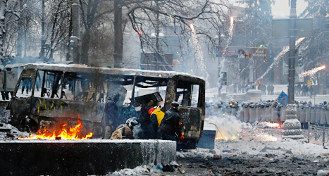 Demonstranter i Kiev gömmer sig bakom en buss som brunnit.
Foto: Sergej Grits/TT.