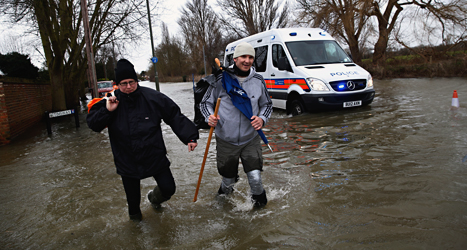Mäniskor i staden Staines-upon-Thames försöker ta sig fram på en översvämmad gata. Foto: Lefteris Pitarakis /AP /TT