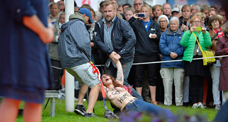 Poliser släpar bort en av kvinnorna som störde Fredrik Reinfeldts tal.
Foto: Henrik Montgomery/TT.