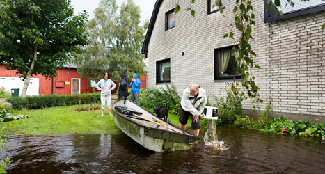 Mikael Jönsson, Camilla Broberg och deras barn får använda båt för att komma ifrån sitt hus. Foto: Anders Andersson /TT