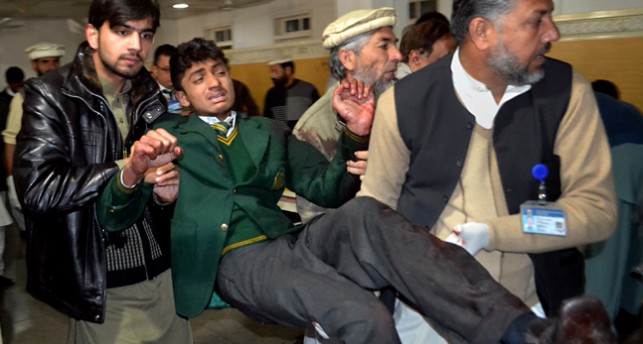 En skadad elev bärs ut från skolan i Peshawar.