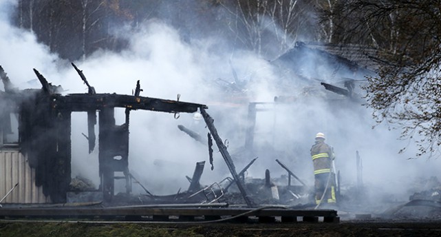 Brandmän vid ett rykande, rasat hus