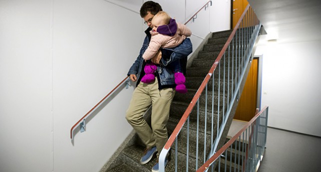 En pappa bär sitt barn nerför en trappa.