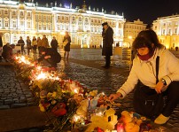 Kvinna lägger blommor vid en minnesplats i Sankt Petersburg.