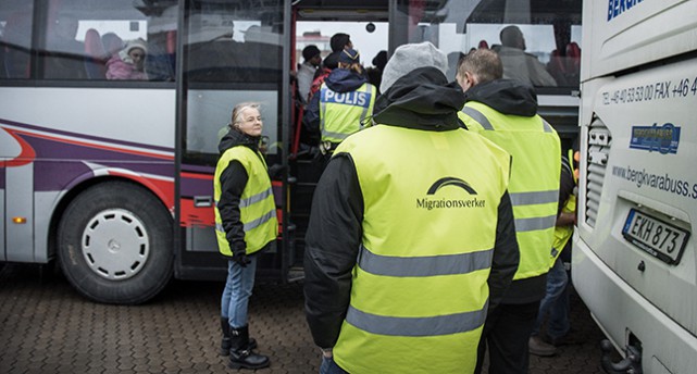 Personal från Migrationsverket möter flyktingar vid buss.