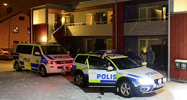Polis vid sin bil utanför hus.