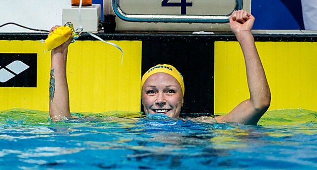 Sarah i bassängen sträcker armarna i luften.
