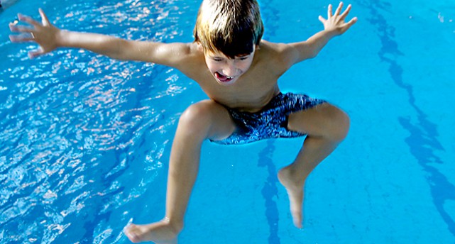 En pojke simmar i en bassäng.