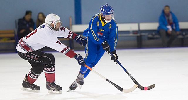 Ett lettisk spelare sträcker sog med klubban efter en svensk anfallare