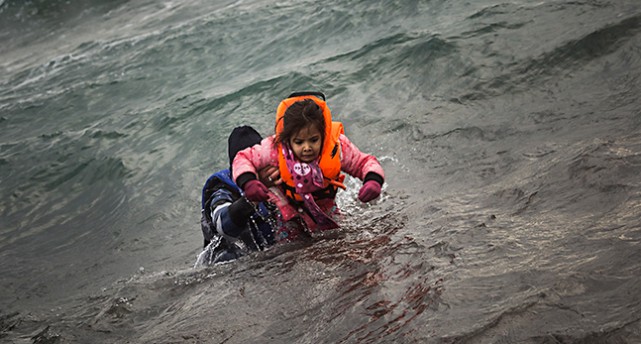 En man bär ett barn ur vattnet mot land