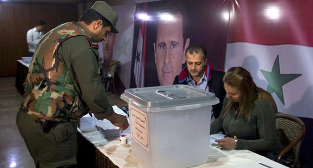 En militärklädd man lägger sin röst i en låda vid ett bord där det sitter två röstmottagare.
