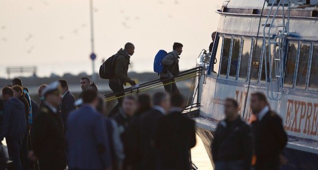 Flyktingar på väg över en landgång in i en båt.