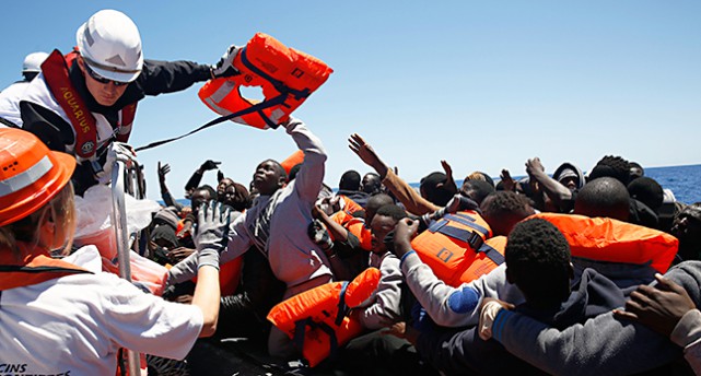 Räddningsarbetare räddar människor från en båt på Medelhavet.