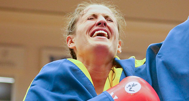 Bea Malecki har svenska flaggan om kroppen och lutar sig bakåt och skrattar. En arm i luften.