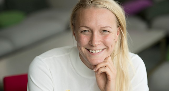 Sarah Sjöström i vit tröja. Hon ler och stödjer huvudet med handen.