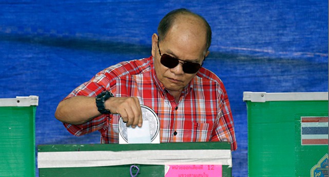 En man stoppar en röstsedel i av låda