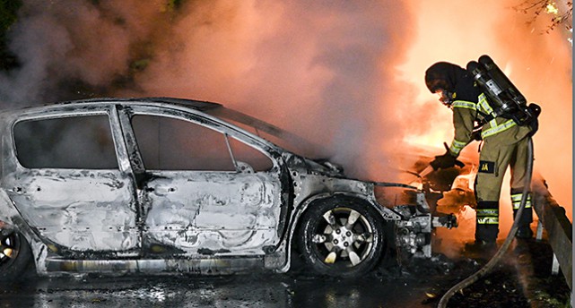 En brandman försöker släcka elden i en bil