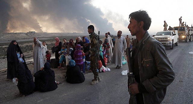 Människor sitter och står på marken efter att ha lämnat staden Mosul.