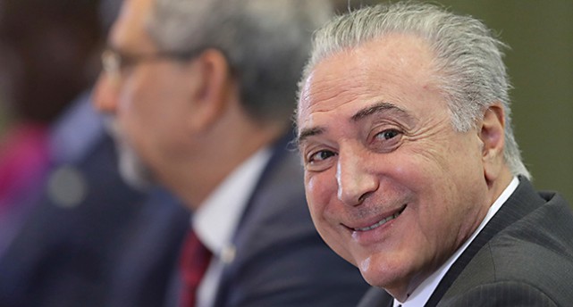 Michel Temer ler mot kameran.