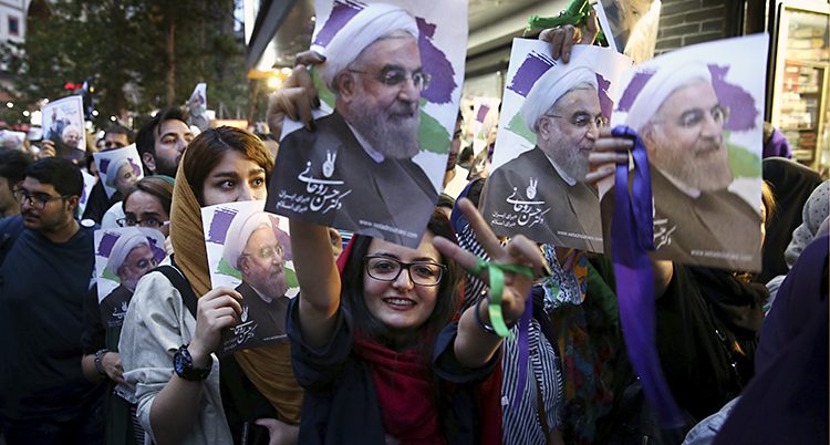 Människor håller upp skyltar med Irans president Rohani.