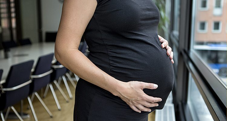 En gravid kvinna håller om sin mage. Hennes ansikte syns inte.