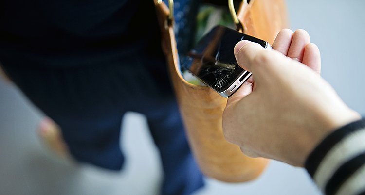 En hand tar en mobil ur en öppen väska