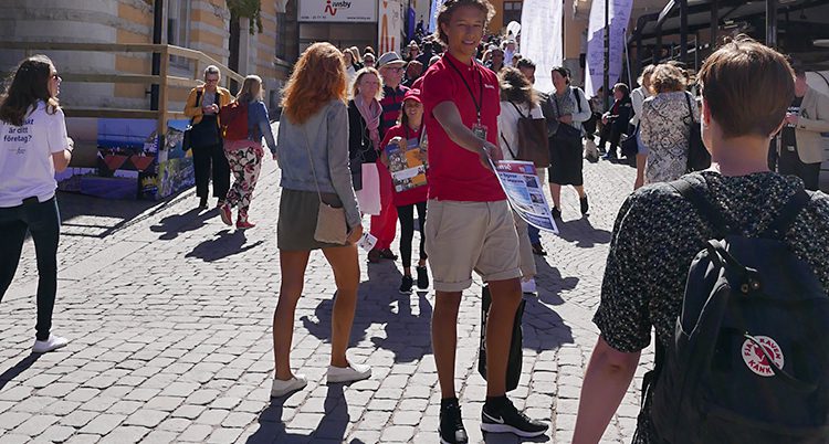 En kille delar ut en tidning på gatan i Visby