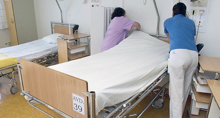 En kvinna bäddar en säng på ett sjukhus