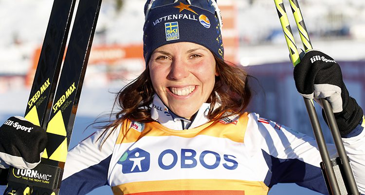 Charlotte Kalla ler och håller upp sina skidor