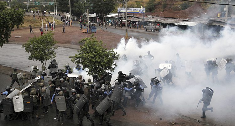 Poliser sprutar tårgas mot demonstranter.